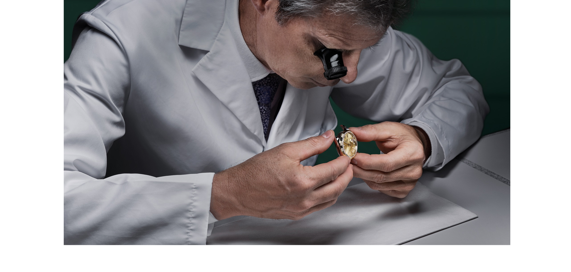 A Rolex watchmaker inspecting a watch with a loupe
