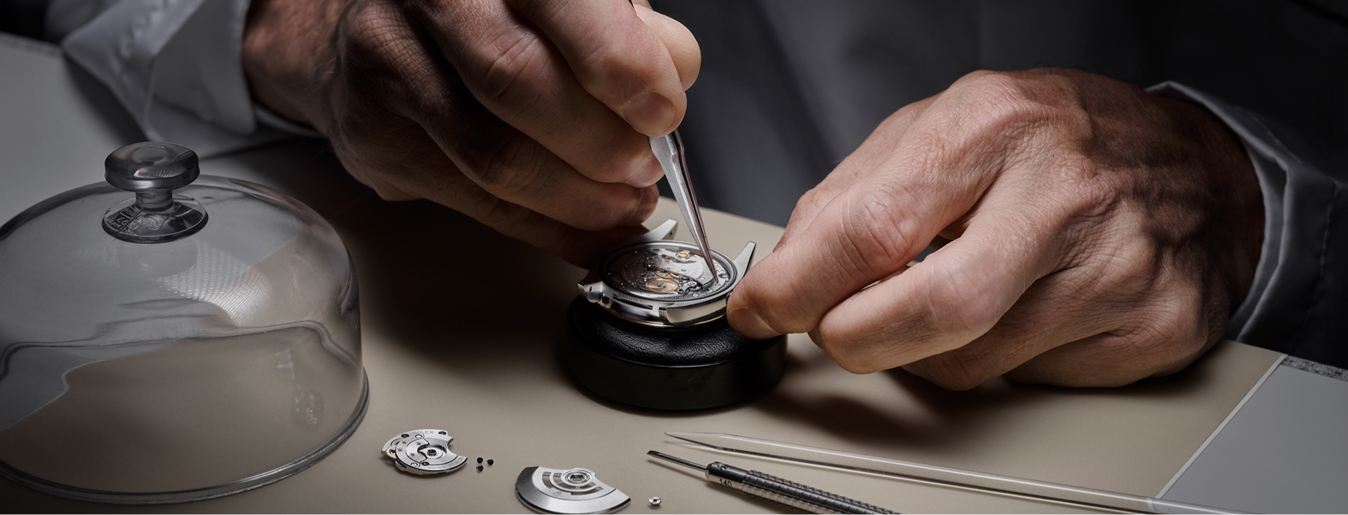 A watchmaker assembling a Rolex movement with tweezers