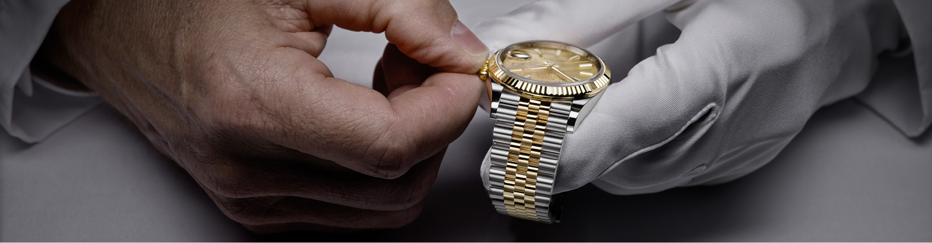 A watchmaker adjusting the winding crown of a Rolex Datejust